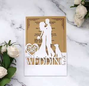 Close-up of laser cut white wedding invitation with Mr & Mrs silhouette and kraft card