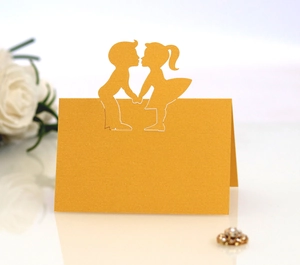 Close-up of golden laser-cut place card featuring a kissing boy and girl silhouette