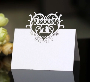 Laser-cut white heart and birds table card for wedding seat decoration on reflective surface