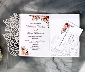 Detail view of laser-cut rose invitation card with floral insert on marble background