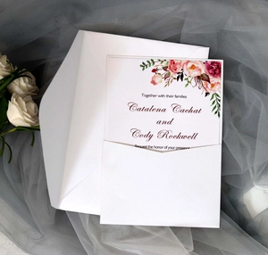 Close-up of elegant wedding invitation with pink watercolor florals and white envelope
