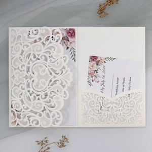 Detail view of laser-cut ivory wedding invitation set with floral inner cards and RSVP cards