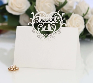 Elegant white laser-cut place card featuring romantic heart and bird motifs for weddings