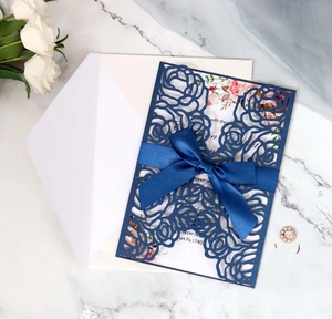 Detailed laser cut floral wedding invitation with navy blue lace cover and satin bow