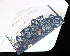 Macro detail of laser-cut floral pattern on navy pearlescent wedding invitation card