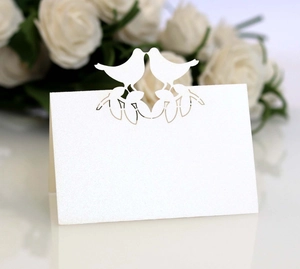 Close-up of laser-cut white birds name place card on elegant pearl paper for wedding