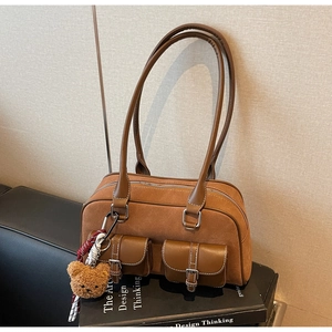 Détail du sac à bandoulière en daim marron avec mini poches et un charmant ours en peluche
