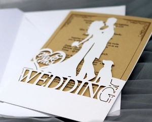 Detail of laser-cut white wedding invitation featuring a romantic silhouette and kraft insert