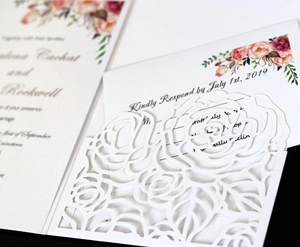 Detail of laser-cut rose hollow wedding invitation with elegant floral inner cards