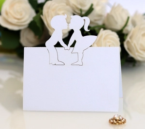 Detail of white laser-cut wedding place card with romantic boy and girl silhouette