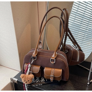 Détail d'un sac Boston vintage marron avec texture en daim et breloque ours en peluche