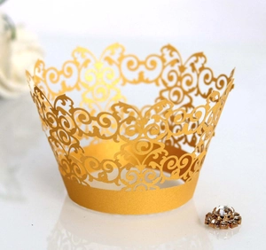 Detail of laser-cut golden cupcake wrapper with elegant scroll pattern for party decor