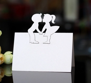 Detail of white laser-cut place card with kissing couple silhouette on pearl paper