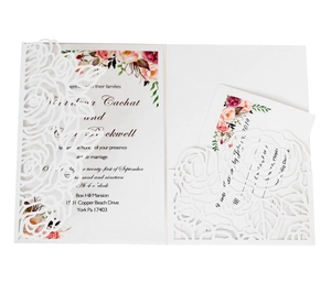 Detailed close-up of white laser-cut floral wedding invitation with floral card insert