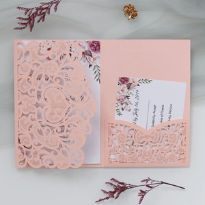 Macro detail of laser-cut peach pink wedding invitation with intricate floral lace pattern