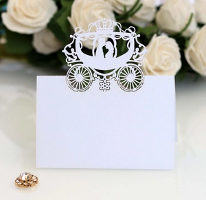 Detail of white laser-cut hollow wedding place card with elegant pumpkin carriage design