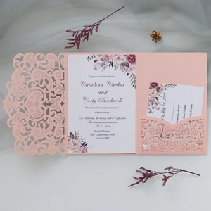 Detail showing pink laser-cut wedding invitation set with floral cards and delicate envelopes