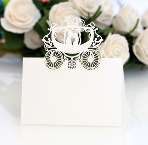Detail of laser-cut white wedding place card with carriage design and couple silhouette