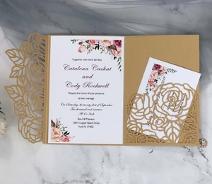 Macro view of laser-cut gold floral hollow pocket with blue rose invitation cards