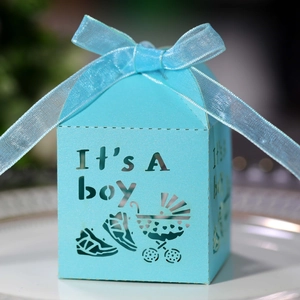 Macro detail of blue laser-cut baby shower candy box with It's A Boy cutout and ribbon