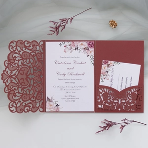 Detail of laser-cut burgundy wedding invitation featuring floral hollow-out design and cards