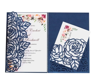 Detail of navy blue laser-cut wedding invitation with intricate rose floral patterns