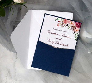 Detail of elegant wedding invitation set with navy laser-cut cover and floral card on marble