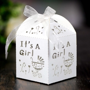Macro detail of white laser-cut 'It's A Girl' baby shower candy box with ribbon