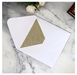 Elegant white V-flap envelope with gold glitter lining on marble surface with white roses
