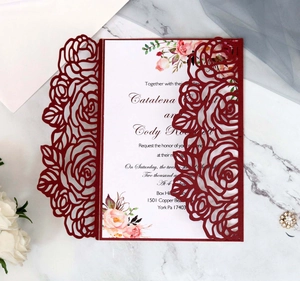 Macro shot of burgundy laser-cut rose wedding invitation with elegant floral inner page
