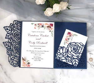 Detailed laser-cut blue wedding invitation card with floral patterns and pink rose insert