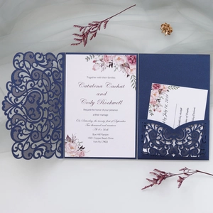 Macro view of laser-cut navy floral invitation cover and printed wedding card