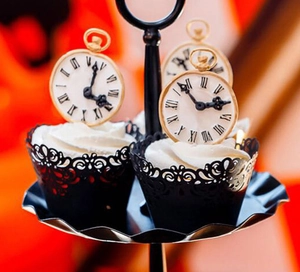 Detail of black laser-cut lace cupcake wrappers with vintage scroll patterns and gold toppers
