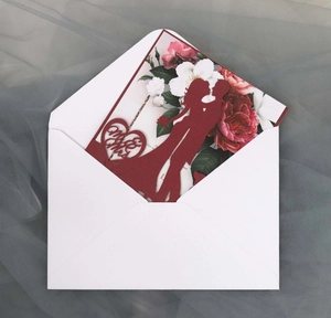 Detail of red laser cut wedding invitation with Mr & Mrs silhouette and white envelope