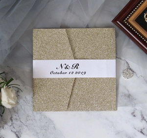 Detail shot of golden glitter wedding invitation with custom white belly band