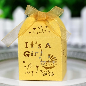 Macro shot of laser-cut 'It's A Girl' yellow baby shower candy box with ribbon