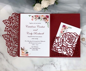 Detailed laser-cut burgundy wedding invitation featuring intricate rose patterns and floral inlay