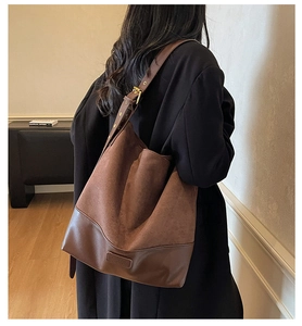 Detail view of large brown suede tote bag with adjustable shoulder strap on model
