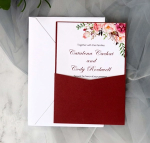 Burgundy frosted wedding invitation set with floral card and white envelope on marble background