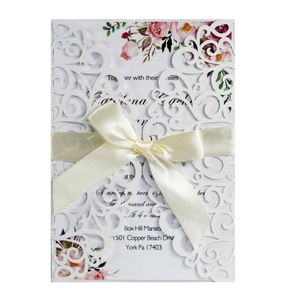Detailed laser-cut lace wedding invitation with cream satin ribbon and floral insert card