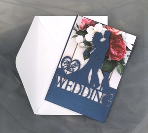 Intricate laser-cut navy blue wedding invitation with silhouettes and floral inner page
