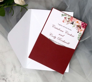 Elegant laser-cut wedding invitation set with floral card, burgundy sleeve, and envelope
