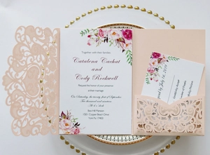 Detailed laser-cut wedding invitation set with floral inner card and RSVP card on white plate