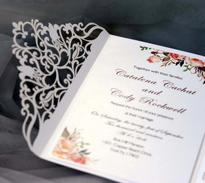 Détail de dentelle découpée au laser sur faire-part de mariage rose clair avec fleurs