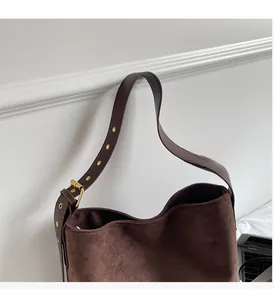Detail of dark brown suede shoulder bag showing adjustable strap and gold metal hardware