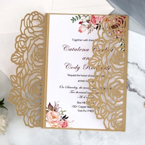 Elegant gold laser cut rose wedding invitation with floral insert on marble background