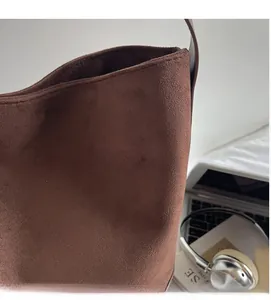 Macro detail of brown faux suede bucket bag fabric with sleek shoulder strap texture