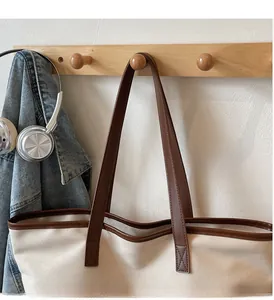 Reinforced stitching detail on the sturdy brown leather handles of the canvas tote bag