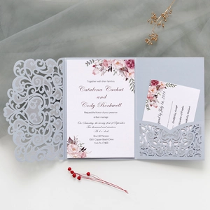 Detail of laser-cut wedding invitation with floral insert on elegant fabric background