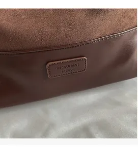 Close-up of retro suede and leather patchwork with embossed WECOCO brand tag